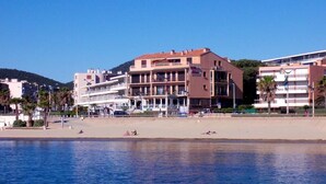 Et kysthotel med flere etager, en strand i forgrunden og en klar blå himmel.