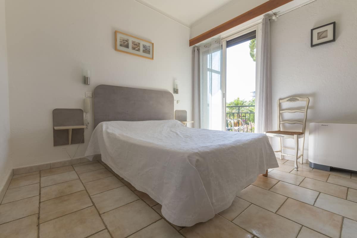 Ein Schlafzimmer mit Bett, Sessel, Tisch und einem Balkon mit Blick.