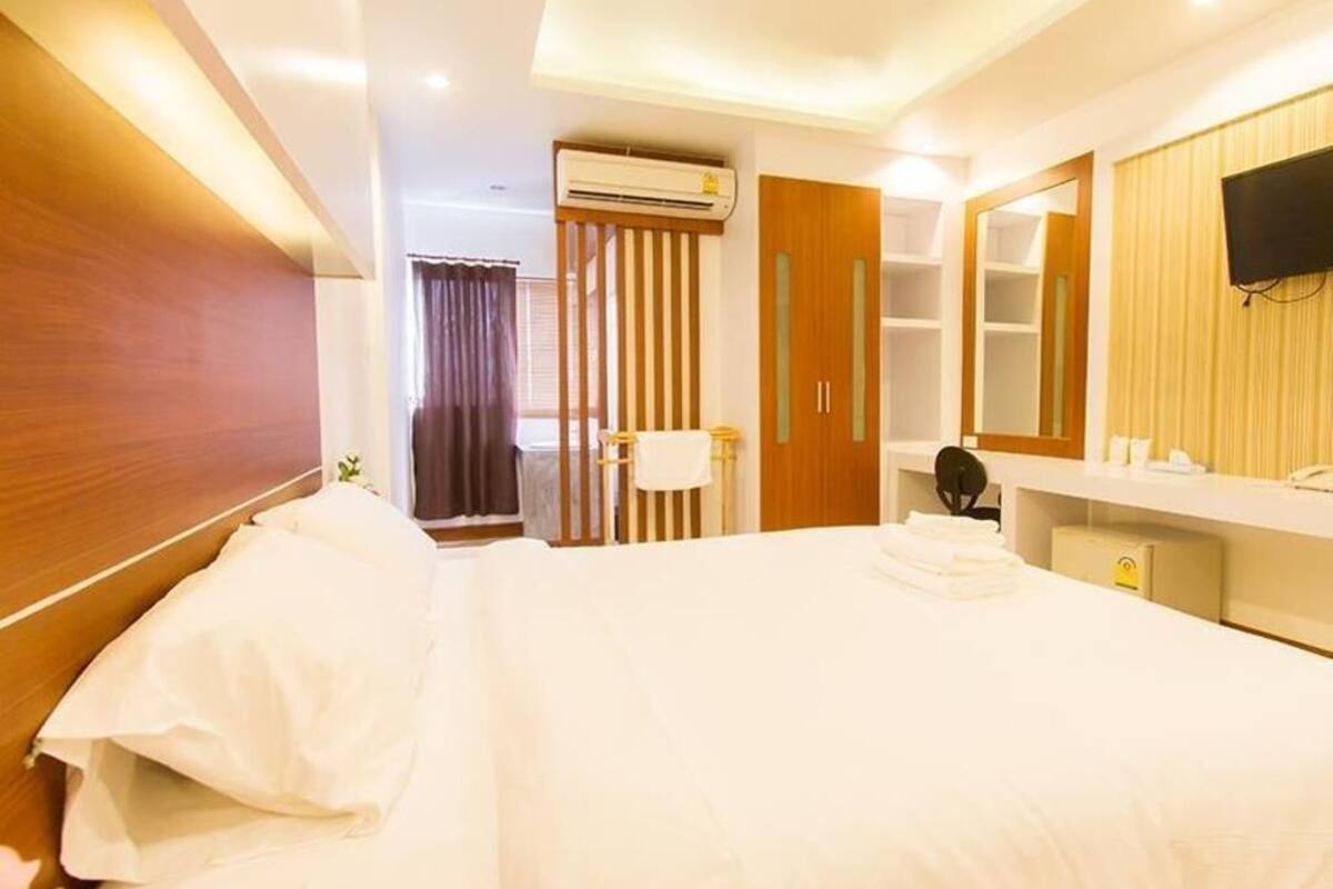 Ein Hotelzimmer mit Bett, Bad, Fernseher und Kleiderschrank.