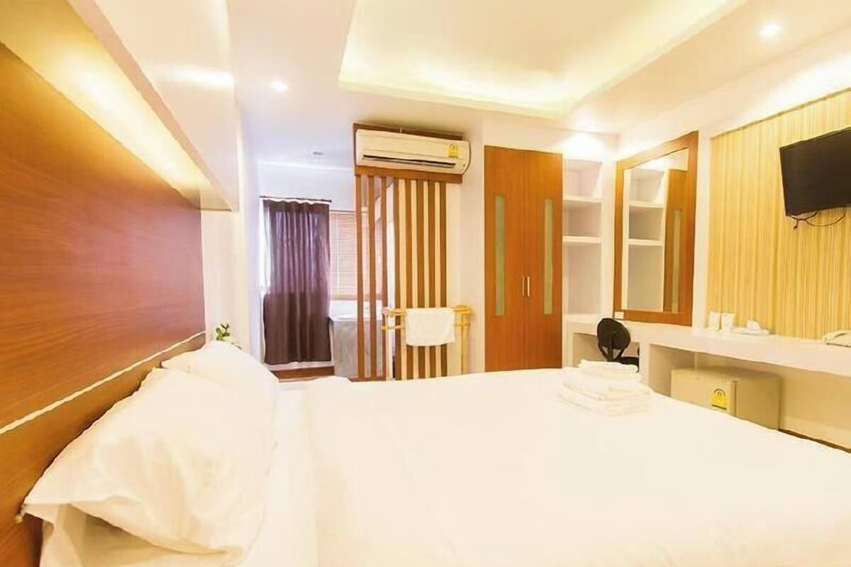 Ein Hotelzimmer mit einem Bett, einem Schreibtisch, einem Spiegel und einer Klimaanlage.