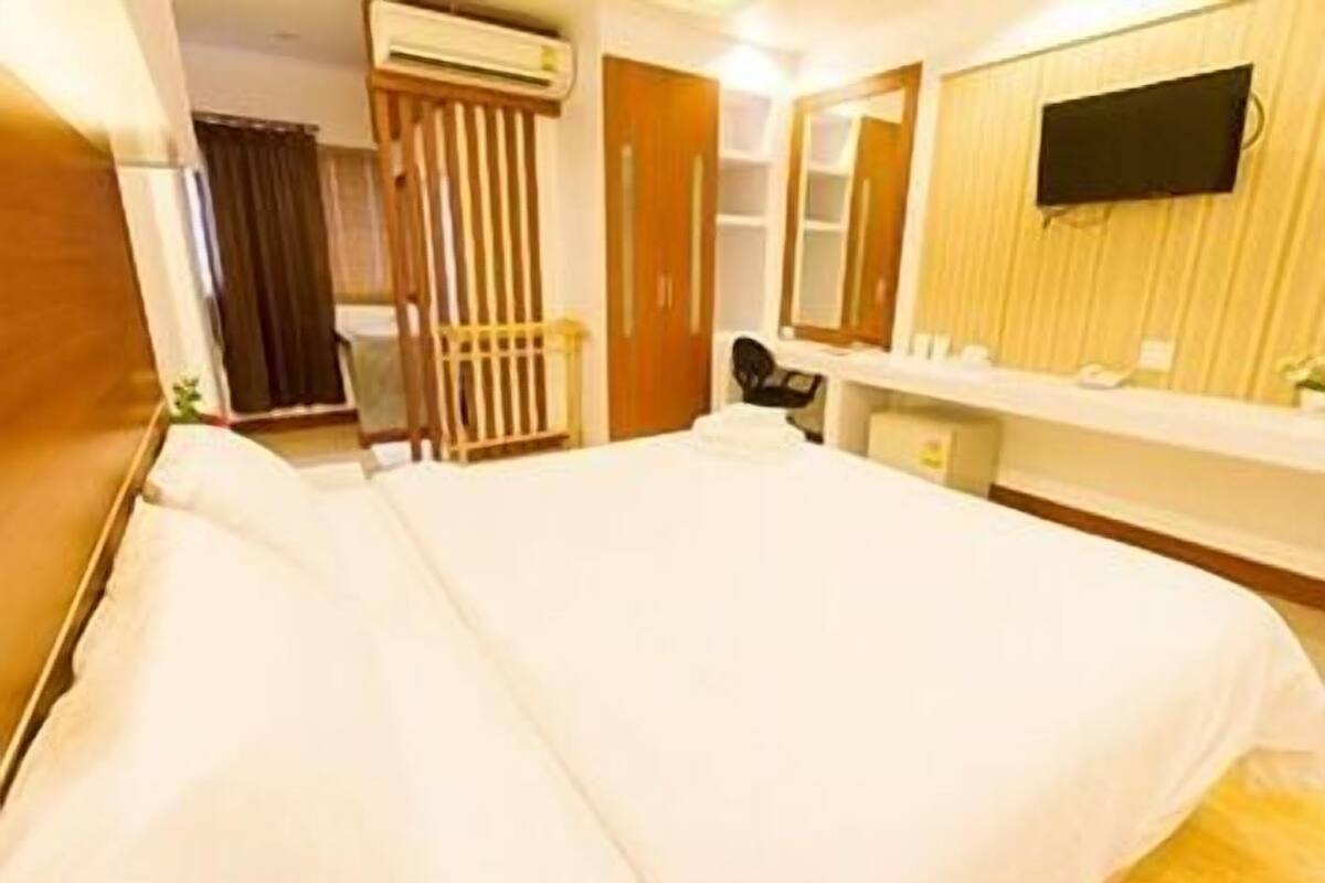 Ein Hotelzimmer mit Bett, Schreibtisch, Stuhl, Fernseher und Kleiderschrank.