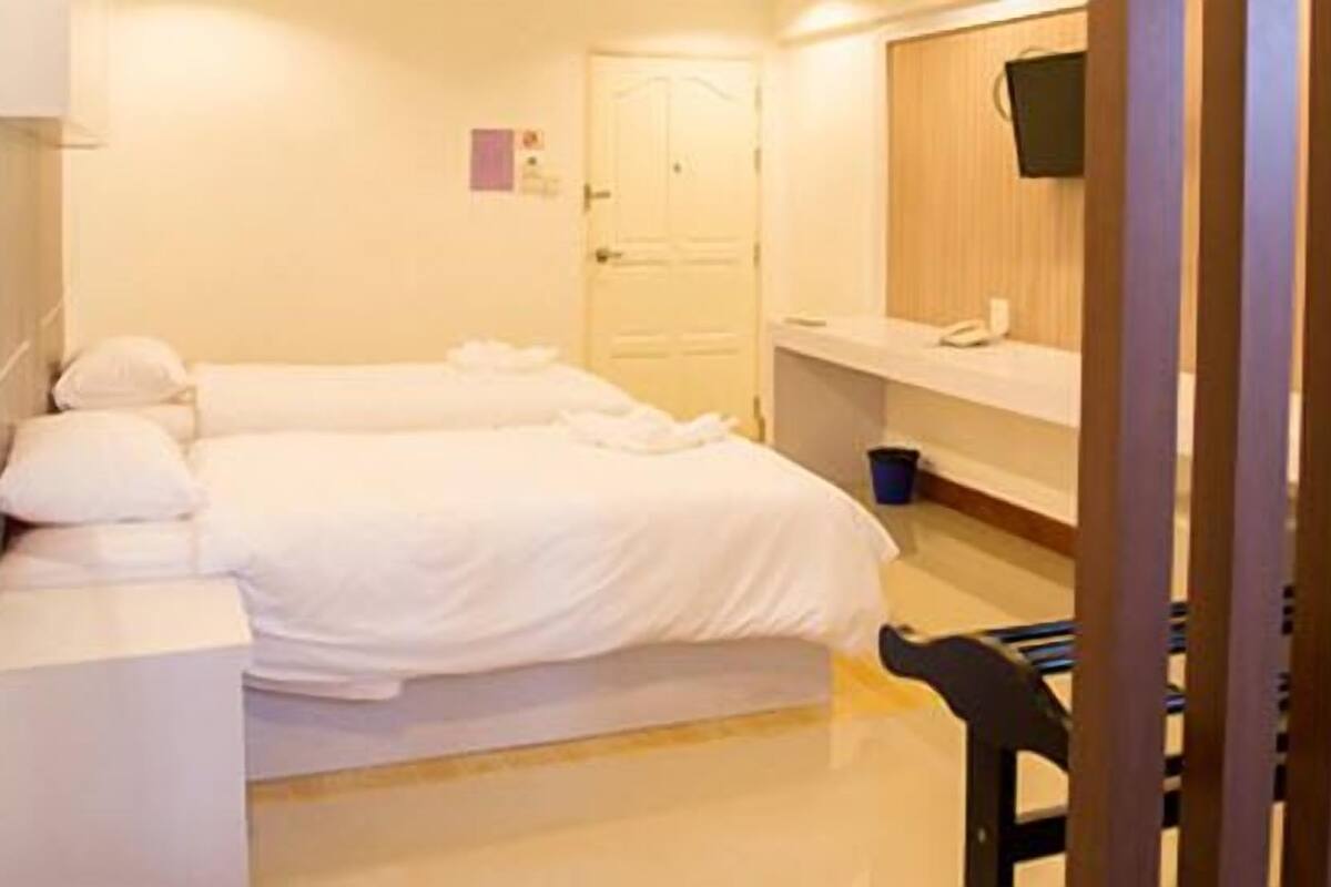 Ein Hotelzimmer mit zwei Betten, einem Schreibtisch, einem Stuhl, einem Fernseher und einer Badezimmertür.