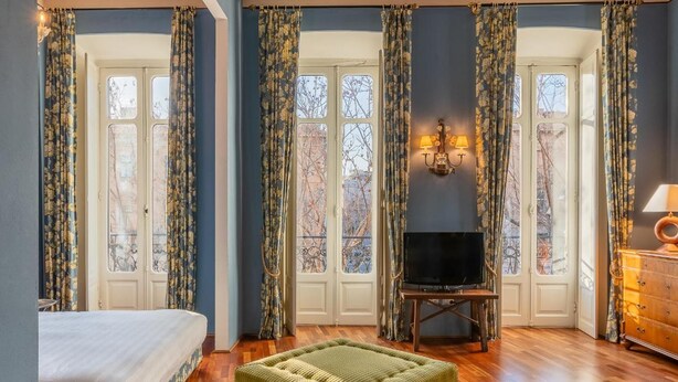 Une pièce spacieuse avec un grand lit, un pouf vert, une télévision et un meuble en bois.