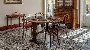 Une salle à manger avec un lustre, un buffet en bois et un tableau accroché au mur.