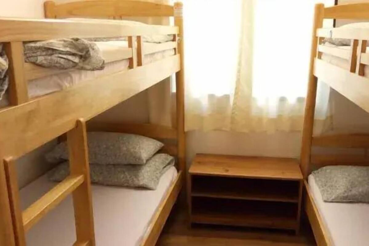 A bunk bed room with wooden frames and gray bedding.