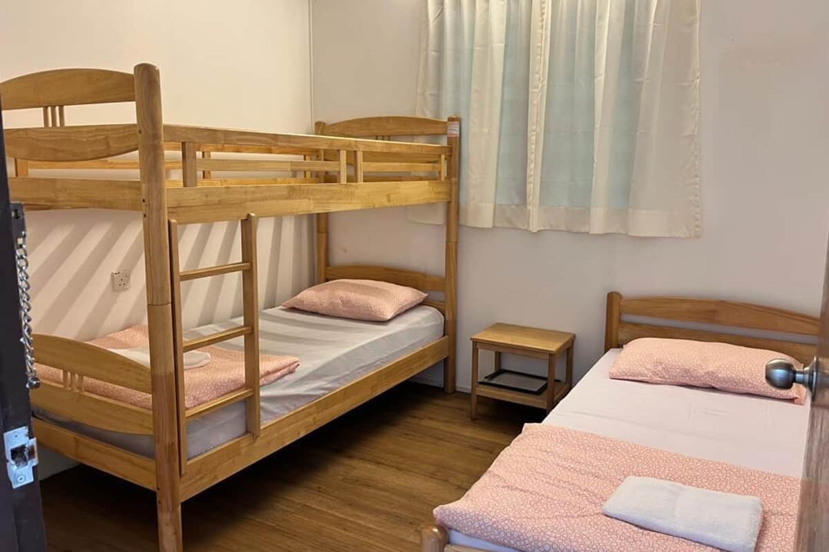 A room with two bunk beds, a small bedside table, and a window with curtains.