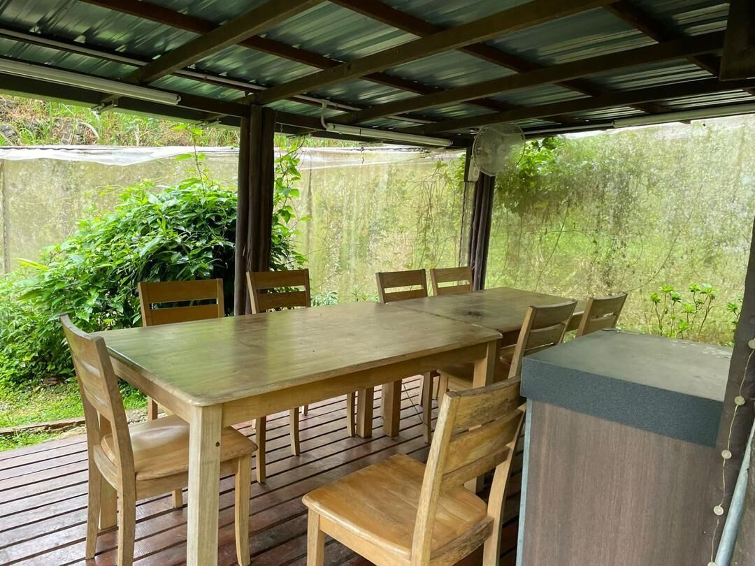 An outdoor wooden deck with a table and chairs, surrounded by greenery.