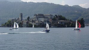 Un lago con veleros y un complejo de edificios históricos al fondo.