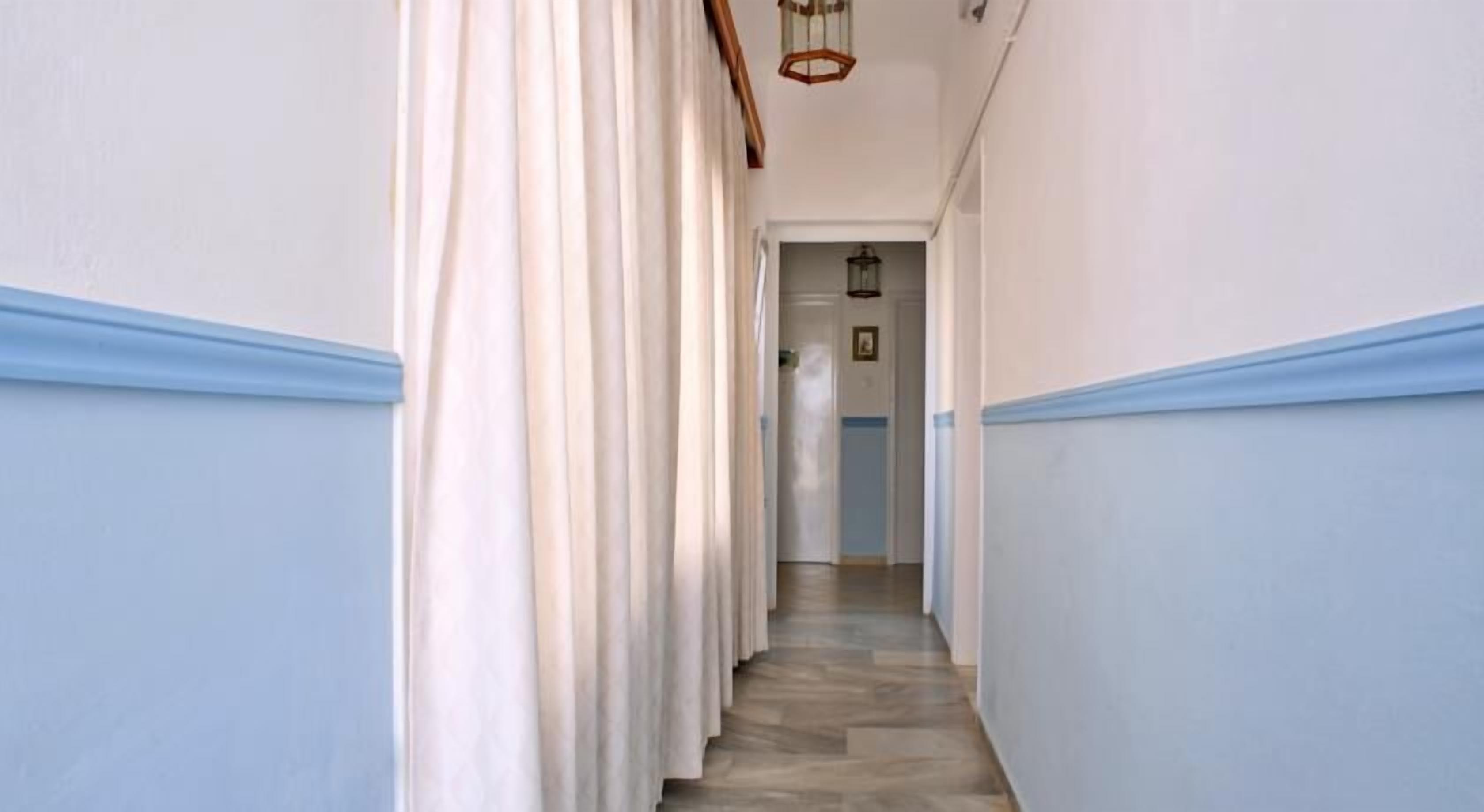 A narrow hallway with light blue walls and a wooden floor.
