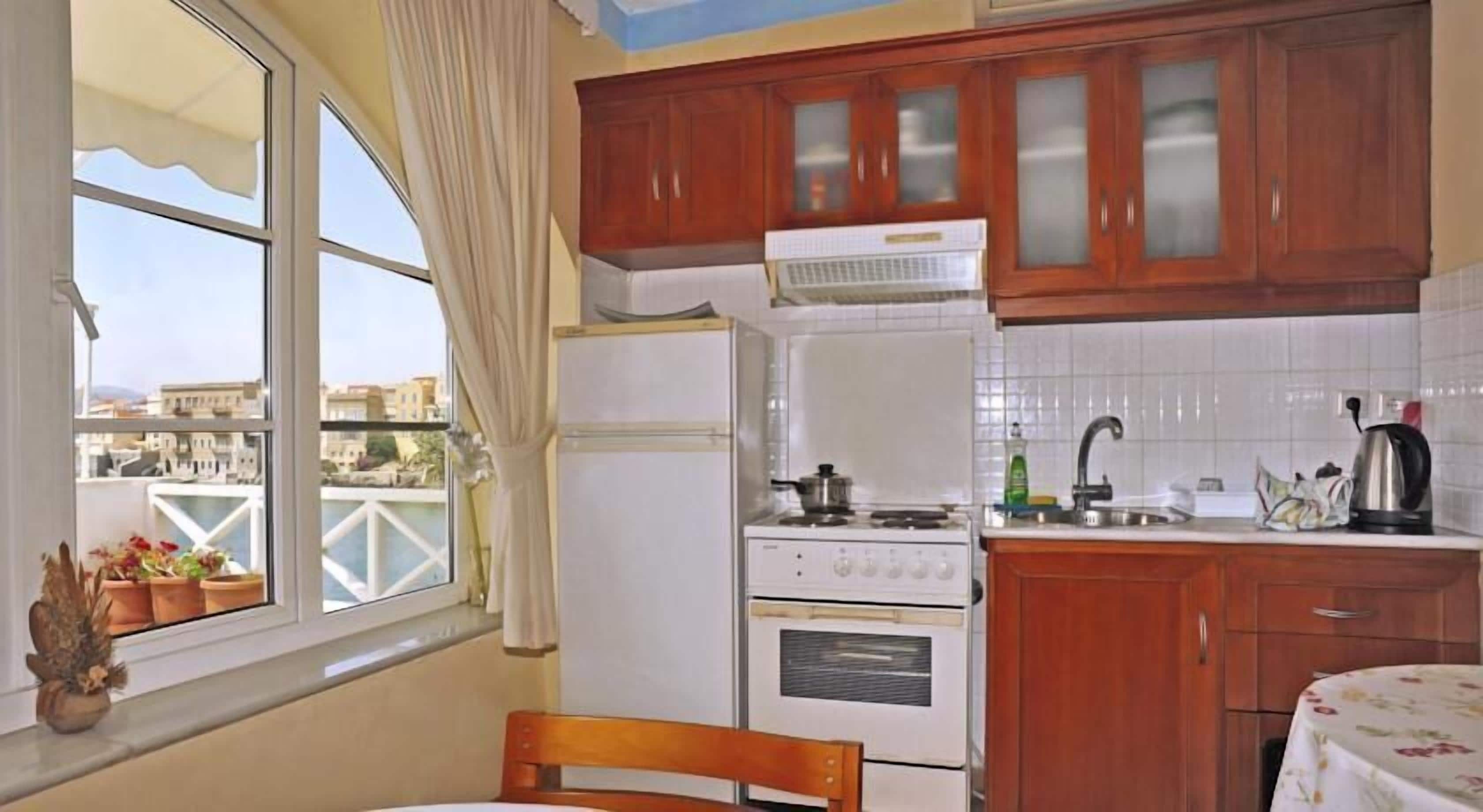 A compact kitchen with wooden cabinets, a refrigerator, a stove, and a sink.
