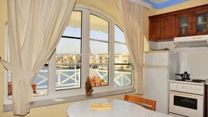 A room with a large window, a dining table, and a kitchen area with a stove and refrigerator.