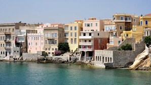 A coastal town with buildings along the waterfront, featuring stone walls and balconies.