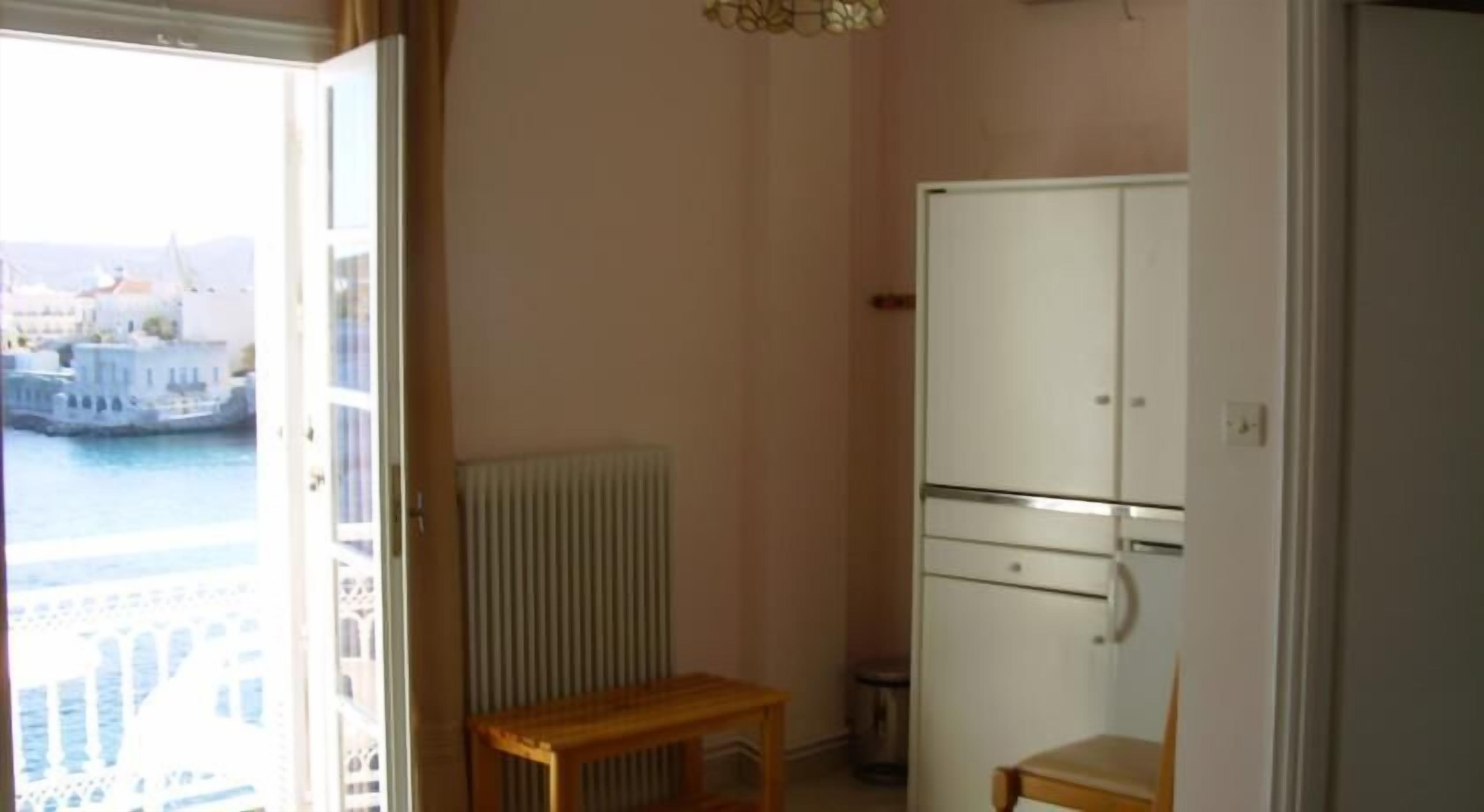 A room with a view of a body of water, a radiator, a wooden table, and a white cabinet.