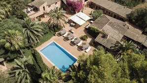 Vue aérienne d’une villa dotée d’une piscine, d’un espace salon extérieur et d’une végétation luxuriante.