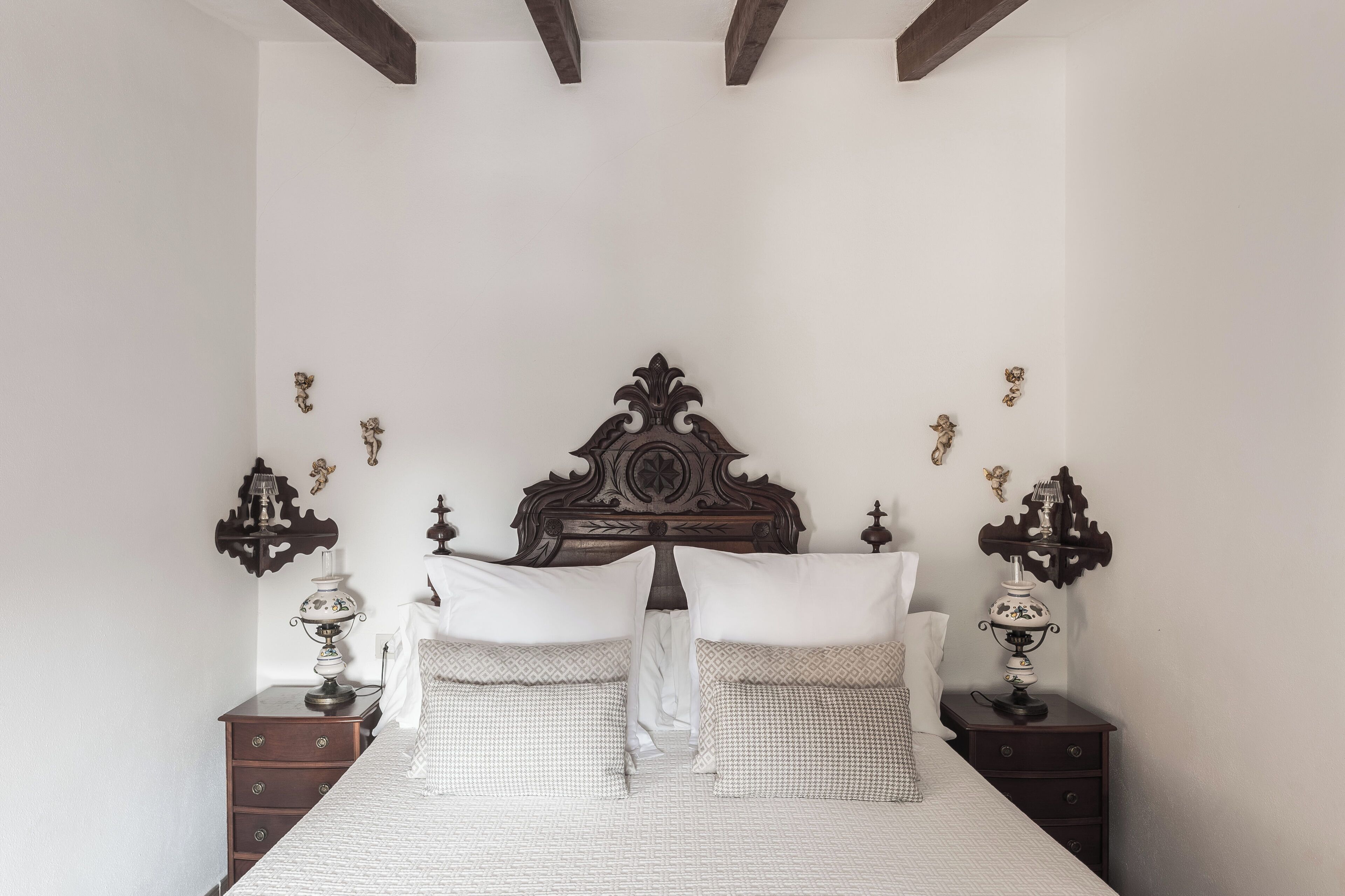 A bedroom with a large bed, two nightstands, and decorative wall sconces.