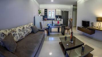 Una sala de estar moderna con sofá, mesa de centro y televisor.
