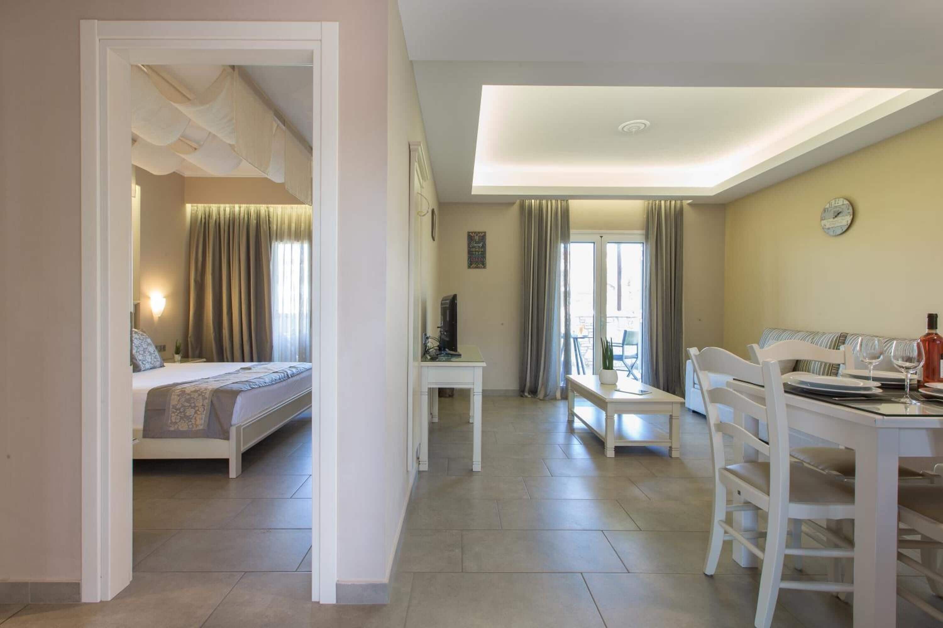 Une chambre d’hôtel comprenant un lit, un bureau, une table à manger avec des chaises et un balcon avec des rideaux.
