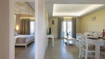 Une chambre d’hôtel comprenant un lit, un bureau, une table à manger avec des chaises et un balcon avec des rideaux.