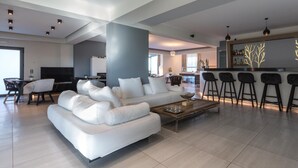 Una sala de estar moderna con un sofá blanco, una mesa de centro y una zona de bar con taburetes.