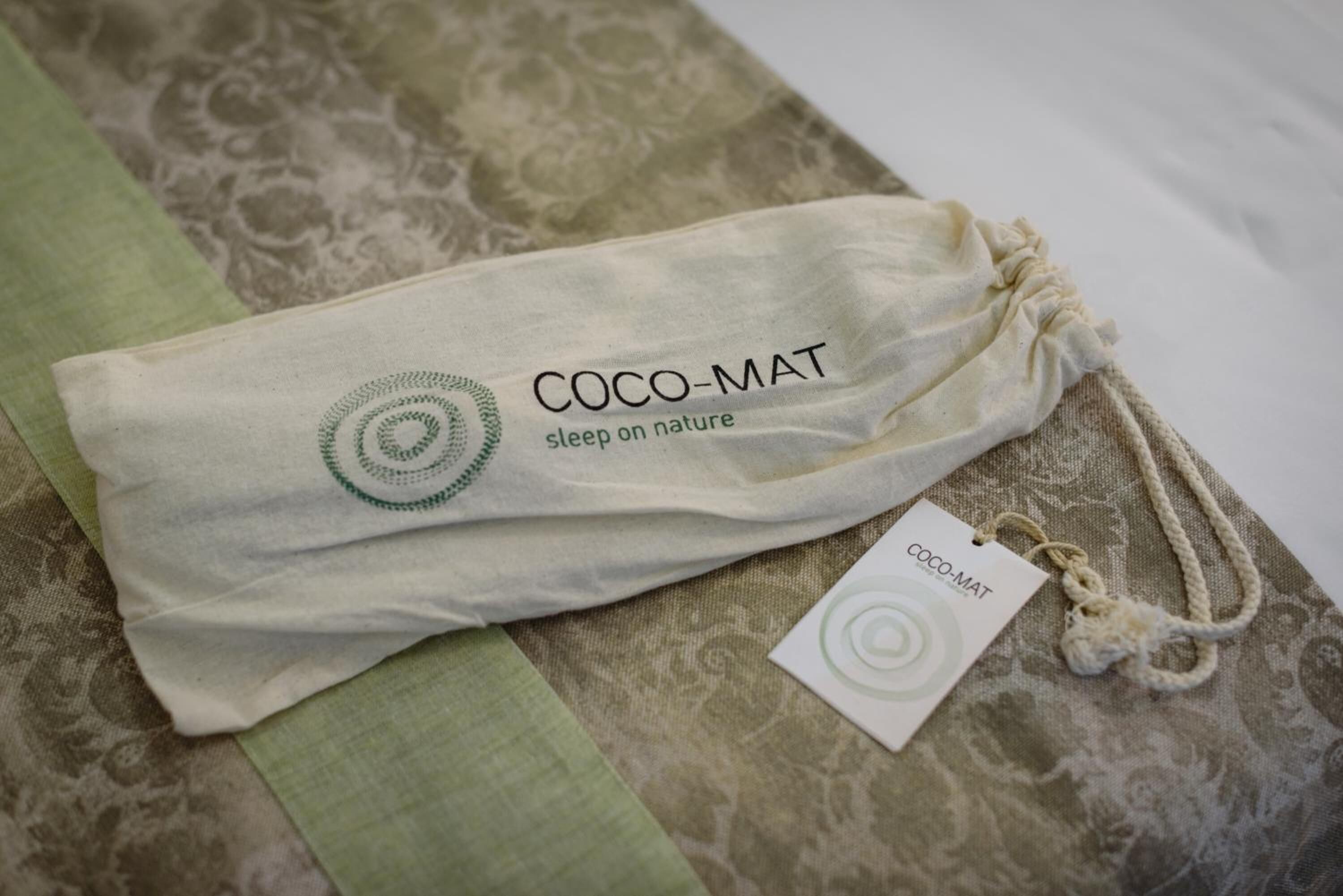 A Coco-Mat sleep bag on a patterned fabric surface.