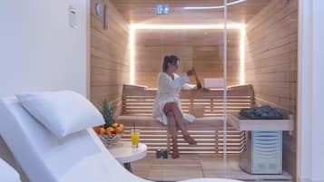 A sauna room with a wooden interior, a massage table, and a small table with fruits and a drink.