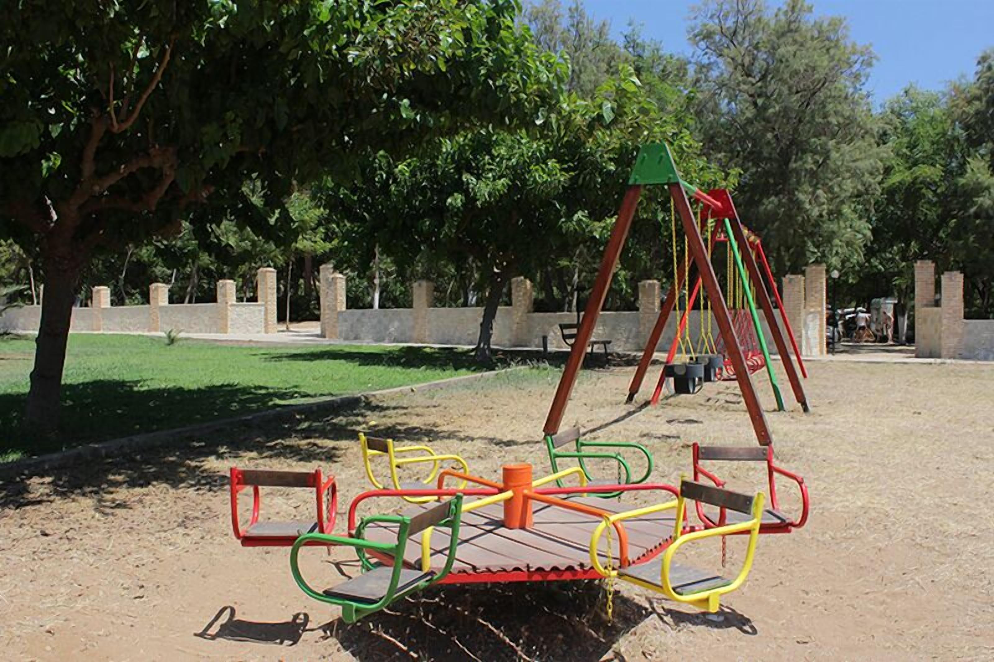 Un parque infantil con columpios, un sube y baja y un carrusel.