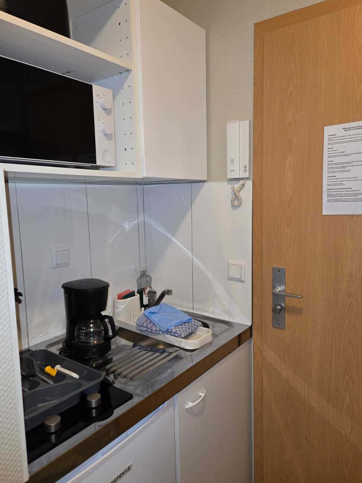 A compact kitchenette with a microwave, coffee maker, and a small sink.