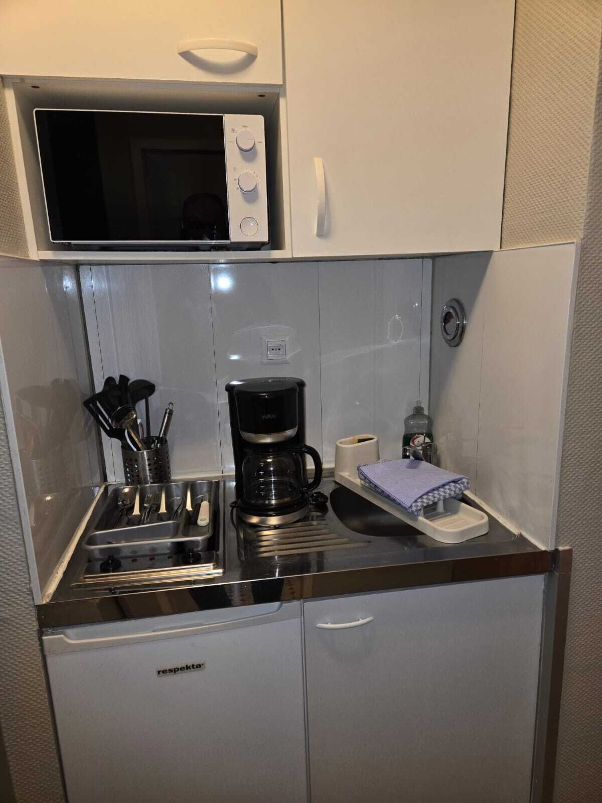 A compact kitchenette with a microwave, coffee maker, and a small sink.