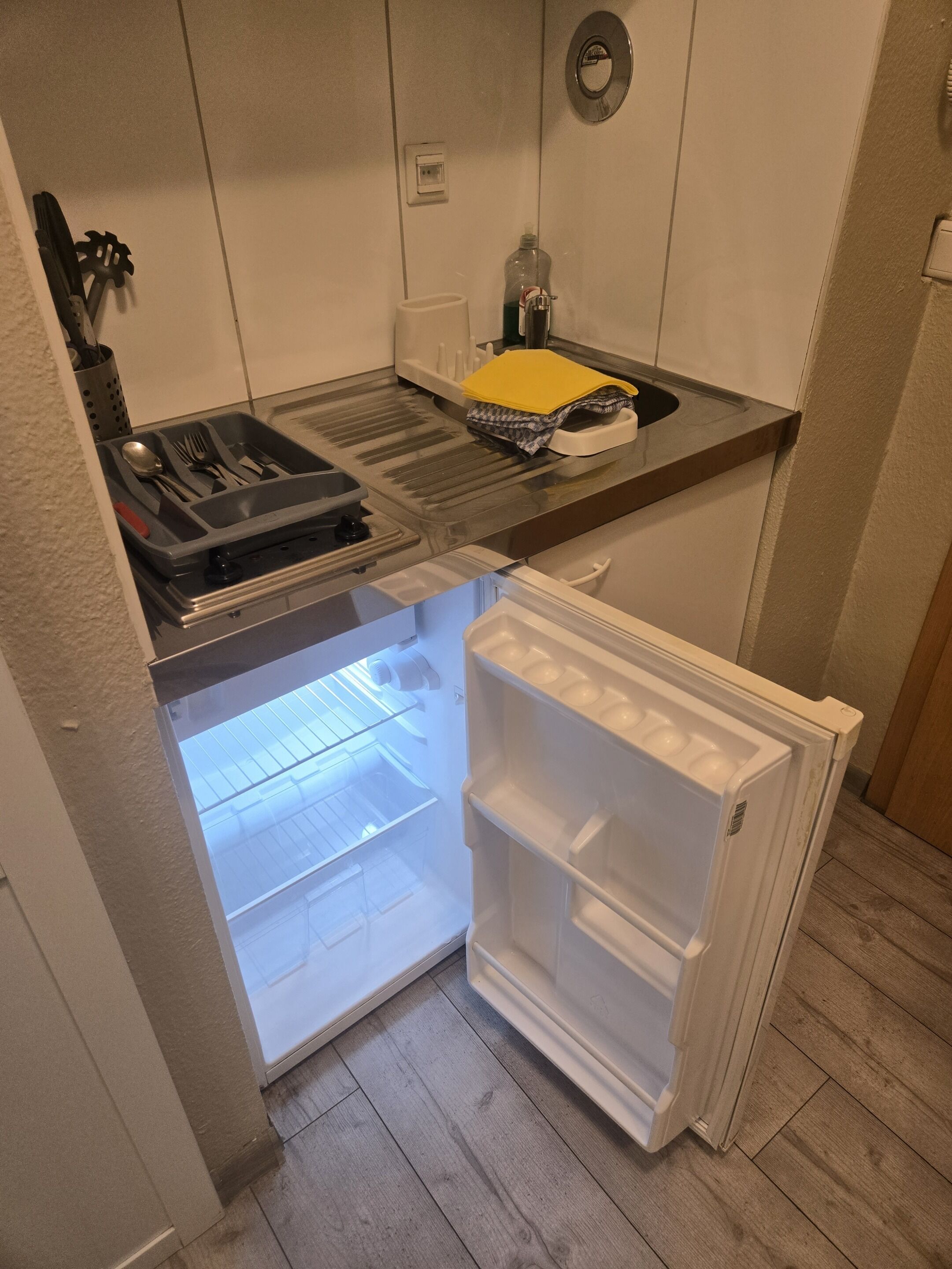 A compact kitchen with a built-in refrigerator, a sink, and a utensil holder.
