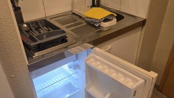 A compact kitchen with a built-in refrigerator, a sink, and a utensil holder.
