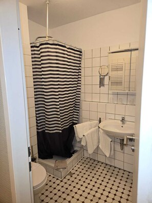 A bathroom with a striped shower curtain, a sink, and a toilet.