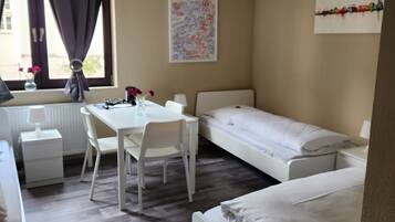 Ein Hotelzimmer mit Bett, Schreibtisch, Stuhl, Tisch und einem Fenster mit Vorhängen.