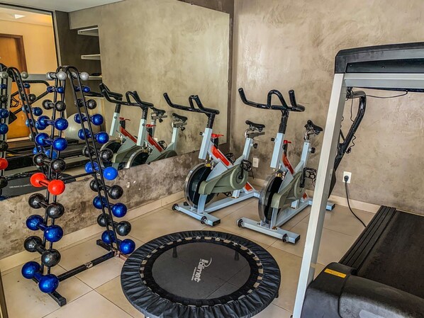 A gym with stationary bikes, a rowing machine, and a trampoline.
