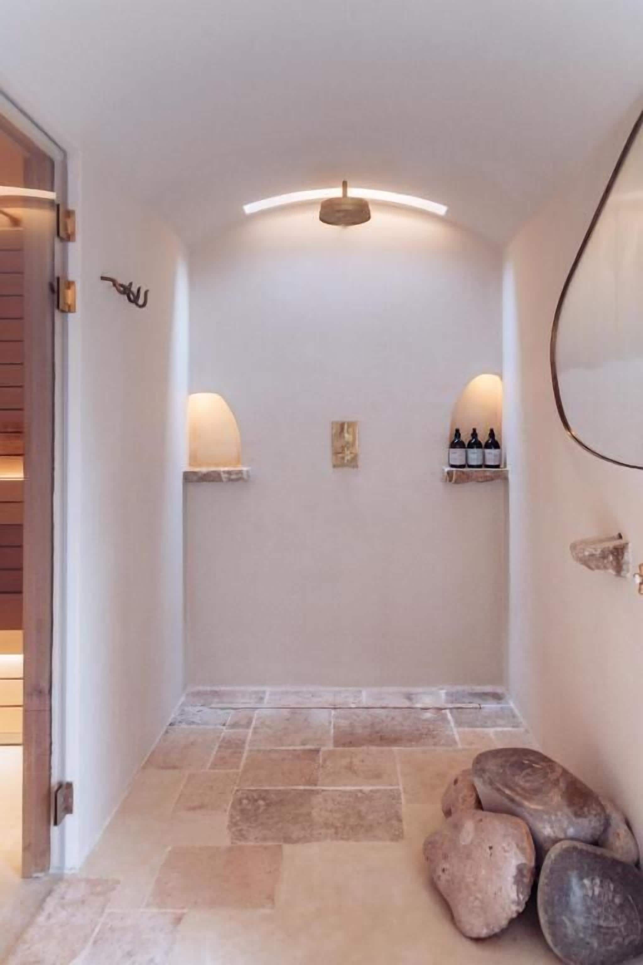 Un pasillo con suelo de piedra, una puerta de madera y una lámpara fijada a la pared.