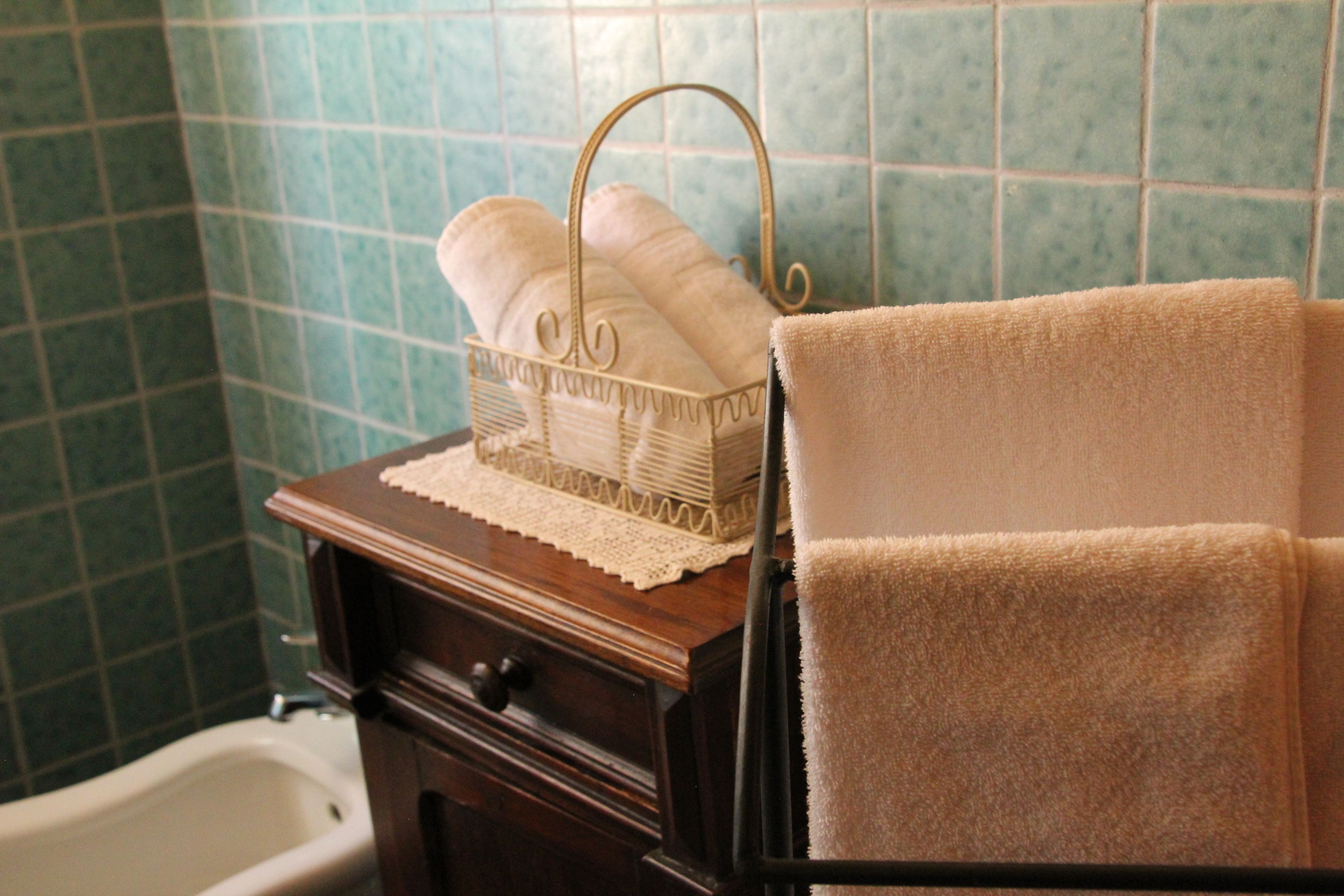 A bathroom with a wooden vanity, a white bathtub, and a towel rack with two towels.