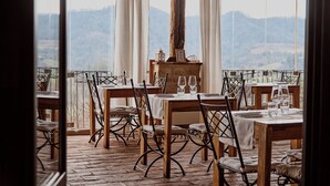 A restaurant with outdoor seating, tables set with white tablecloths and wine glasses, and a view of a mountainous landscape. - Agriturismo Ca San Sebastiano Wine Resort & Spa (Camino)
