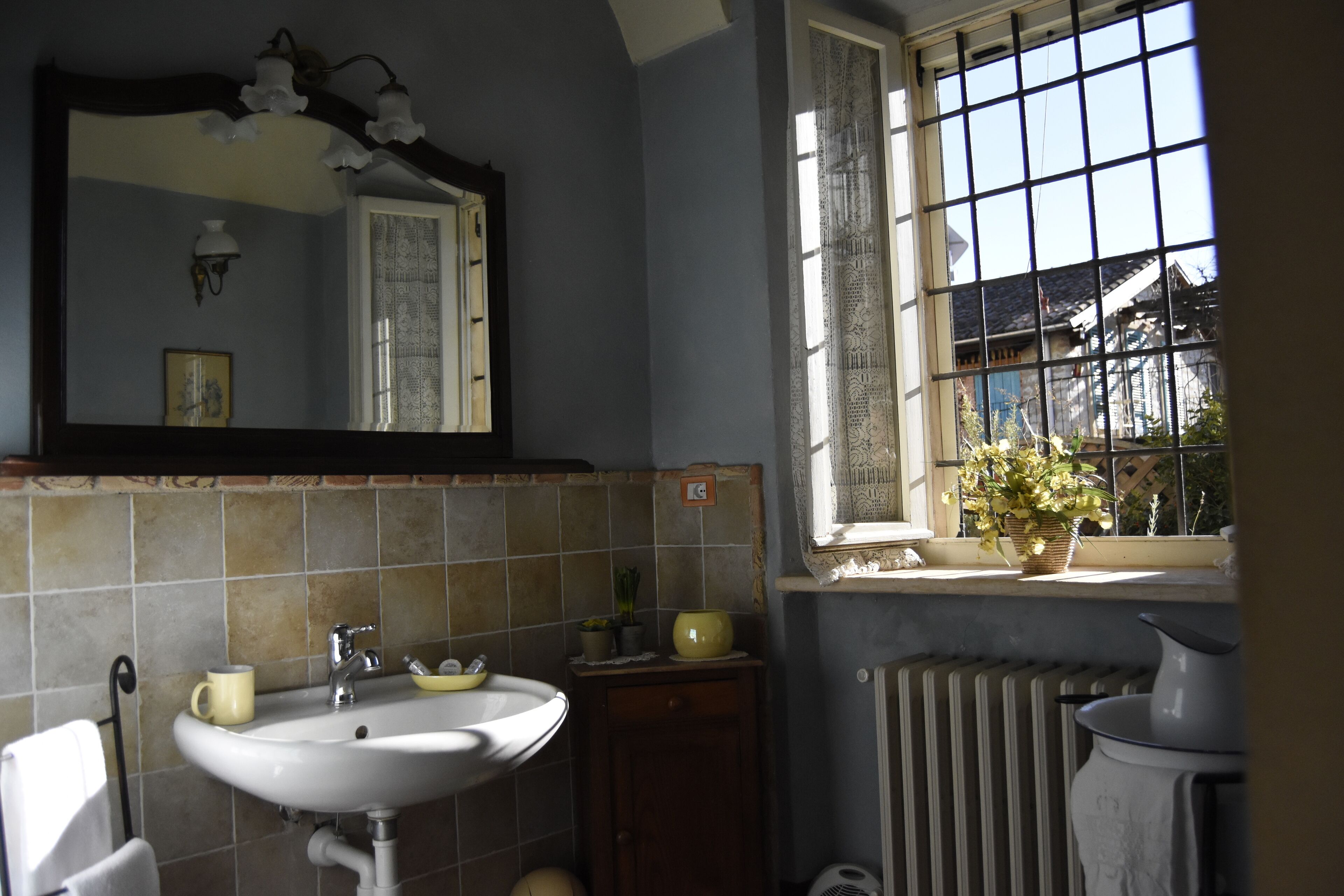 A bathroom with a sink, mirror, and window with a view of the outside.