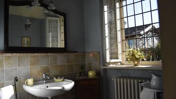 Een badkamer met een wastafel, spiegel en raam met uitzicht.