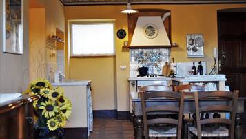 A kitchen with a dining area, featuring a stove, chairs, and a vase of sunflowers.