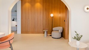 Un interior moderno con una pared de acento de madera, una mesa redonda, una silla y una lámpara de pie.