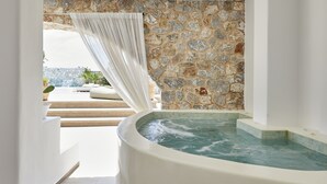 Un área de spa con hidromasaje, paredes de piedra y vistas al exterior.