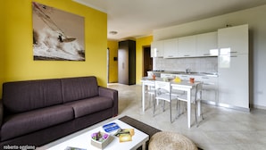 A modern living room with a sofa and a dining area with a table and chairs. - Residence L'isola Surf House (Palau)