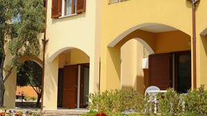 A two-story building with a yellow facade, brown shutters, and a balcony with metal railings. - Residence L'isola Surf House (Palau)