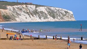 A beach with people, a cliff, and a lifeguard tower. - Endeavour House (Cowes)