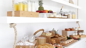A buffet setup with various food items, drinks, and decorative plants on white shelves. - Livin Mykonos Hotel - Adults Only by Mr and Mrs White (Mykonos)