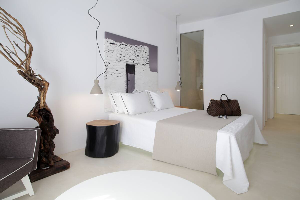 A modern bedroom with a bed, bedside table, lamp, and a decorative tree sculpture.