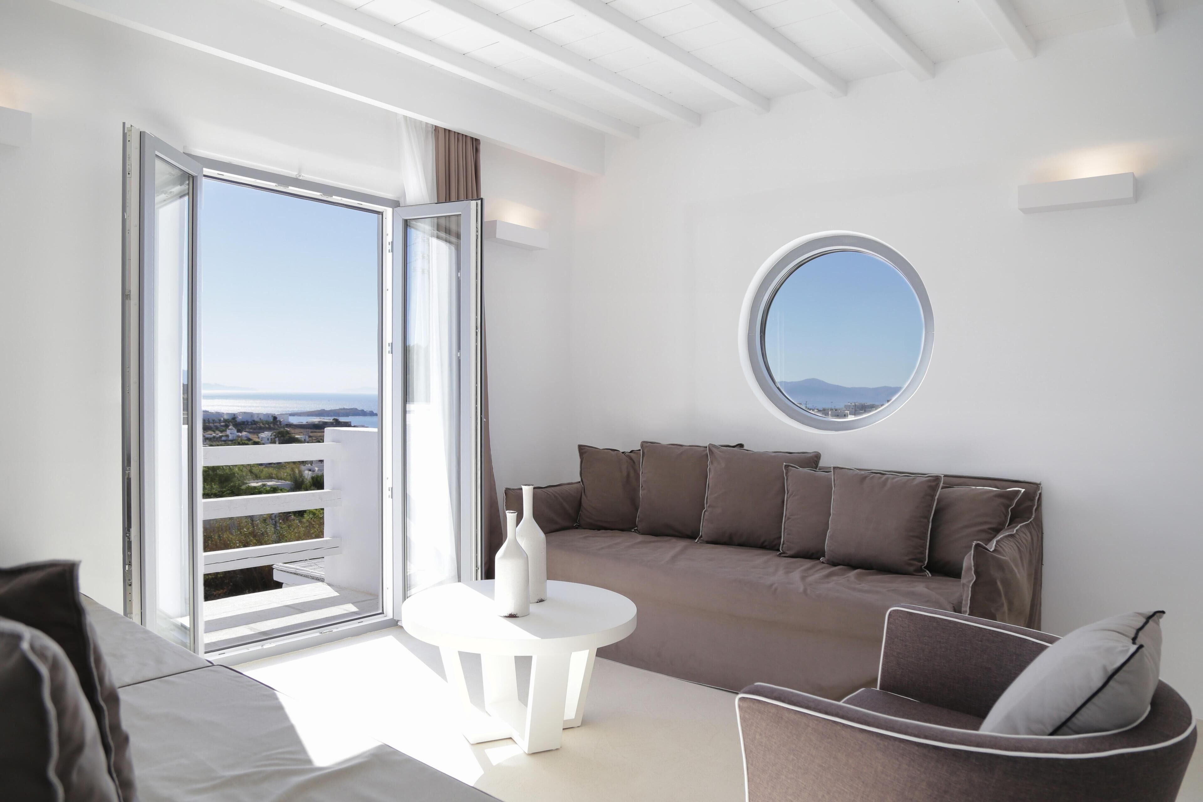 A modern living room with a sofa, a round table, and a view through a sliding glass door to the outdoors.