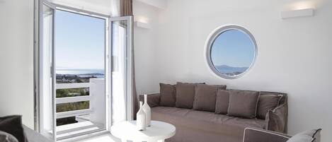 A modern living room with a sofa, a round table, and a view through a sliding glass door to the outdoors.