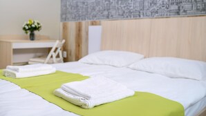 A hotel room with a neatly made bed, a desk with a chair, and a wall with a cityscape mural. - Urban Hotel (Lviv)