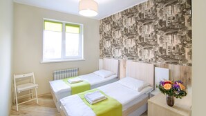 A hotel room with two beds, a radiator, a window with blinds, and a cityscape wallpaper. - Urban Hotel (Lviv)